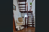 Beige stair lift installed along a wooden staircase inside a house